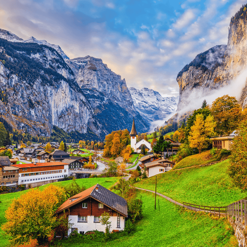 Houses on a green hill with snowy mountains in the background in Lauterbrunnen, Switzerland